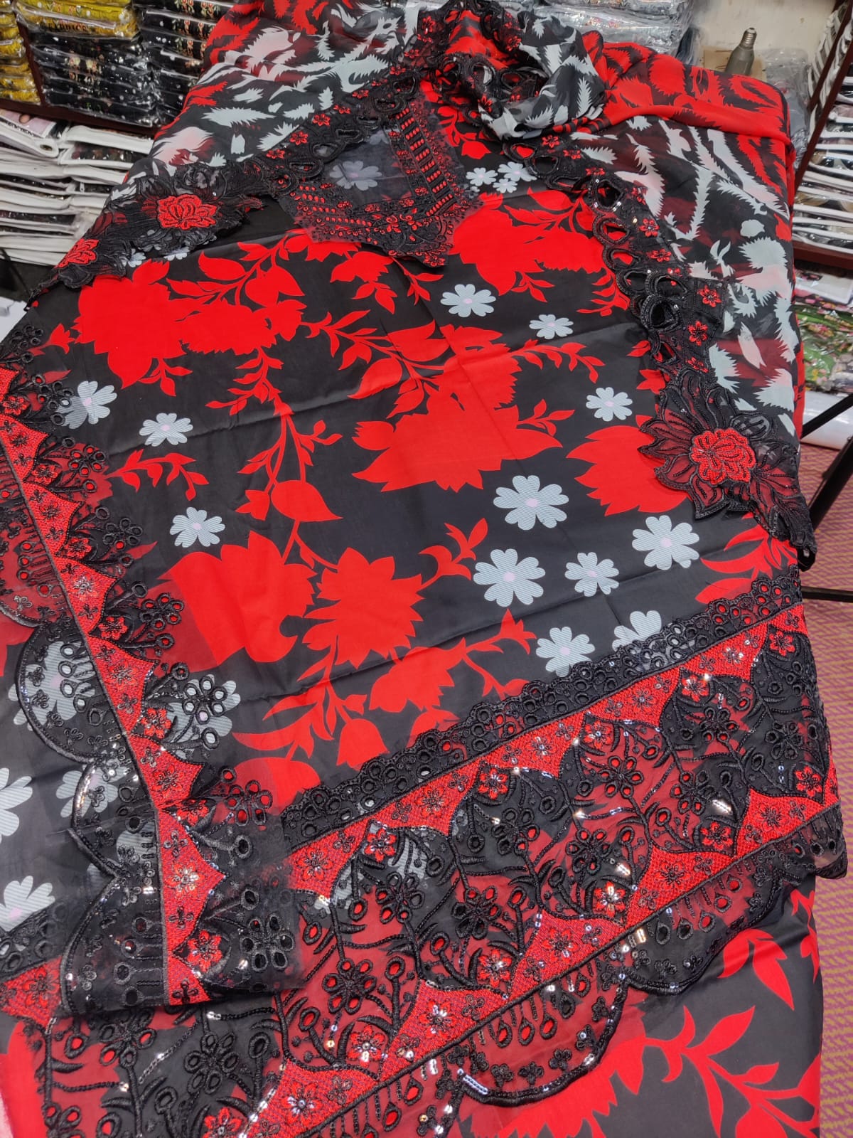 Red and black Ramsha fabric from Danish Cloth, showcasing vibrant colors and intricate woven patterns in a close-up image.