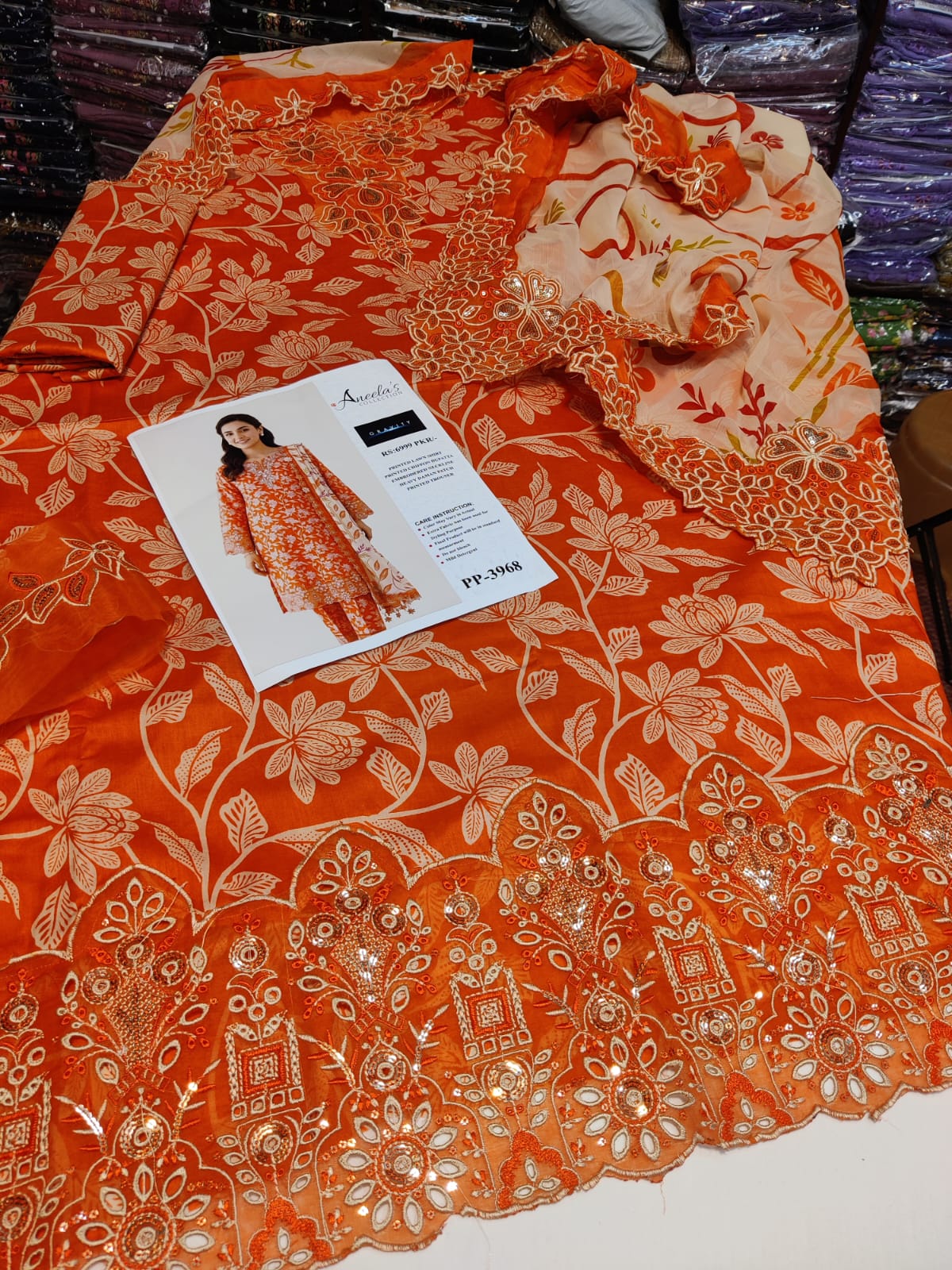 Danish Cloth Aneela's orange Agha featuring vibrant orange fabric with intricate patterns and traditional design.